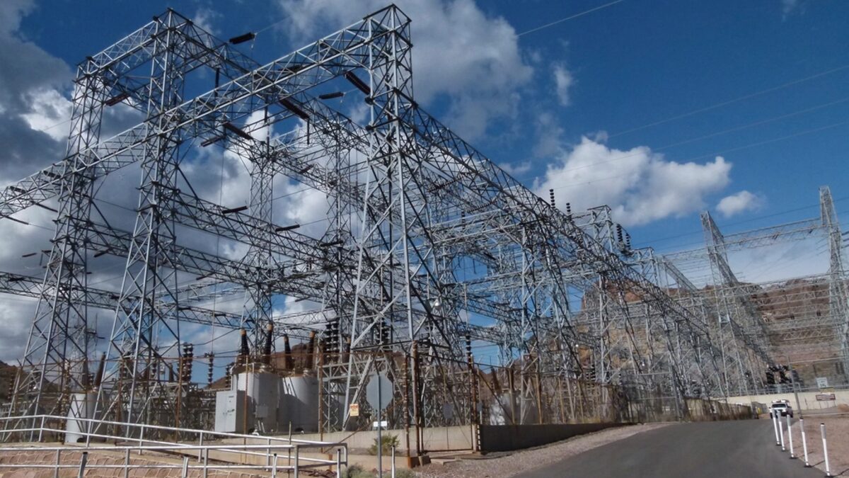 High-voltage transmission lines and pylons against the sky — world grid voltage standards